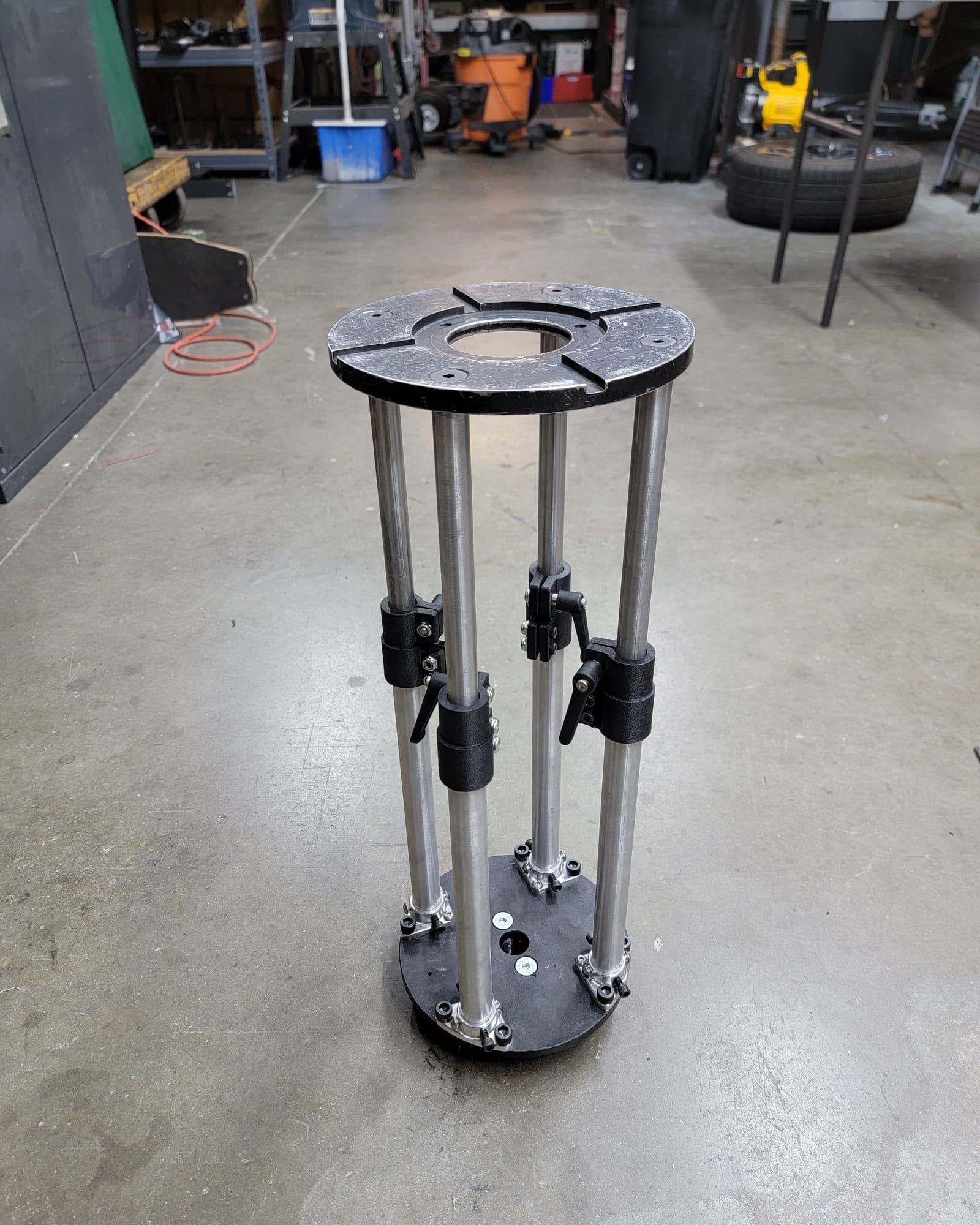 Custom-machined camera riser on polished posts with locking clamps, on the floor of the Fluid Pictures shop