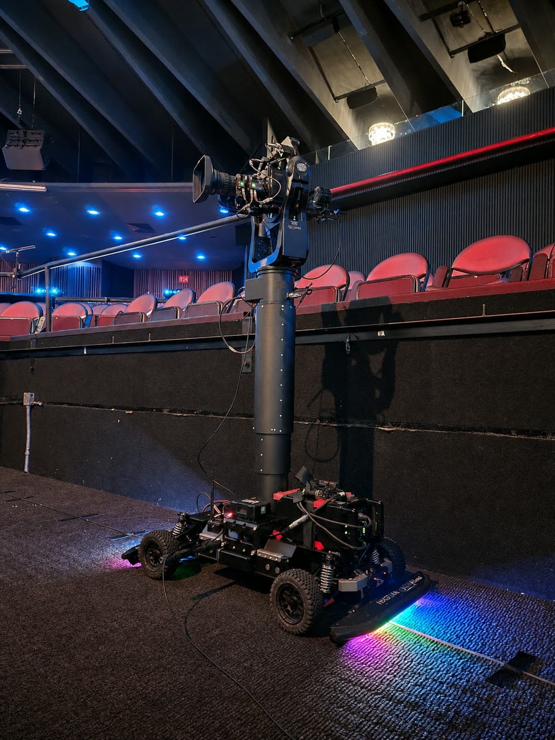 Fluid Pictures Agito robotic camera dolly operating beside theater seating under red and blue lighting