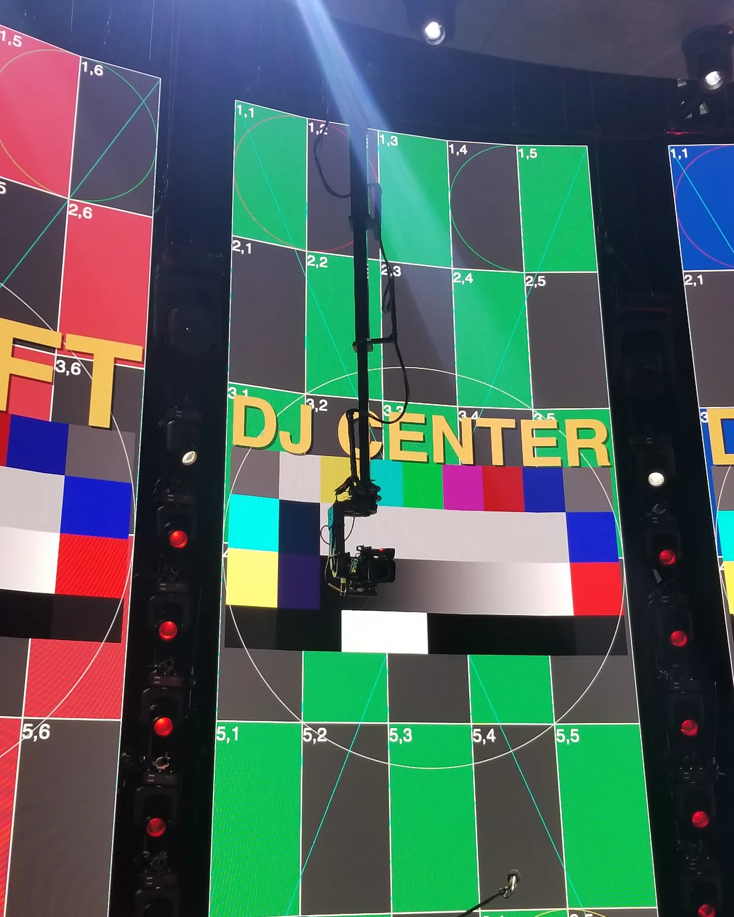 Twin Peek hanging inverted from the grid, lowering a camera in front of an LED wall showing test patterns