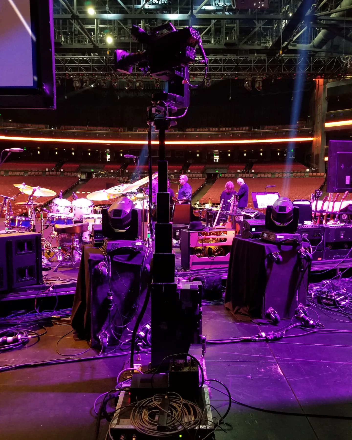 Towercam XS+ raised to full height with a camera on top, among the band gear on an arena stage
