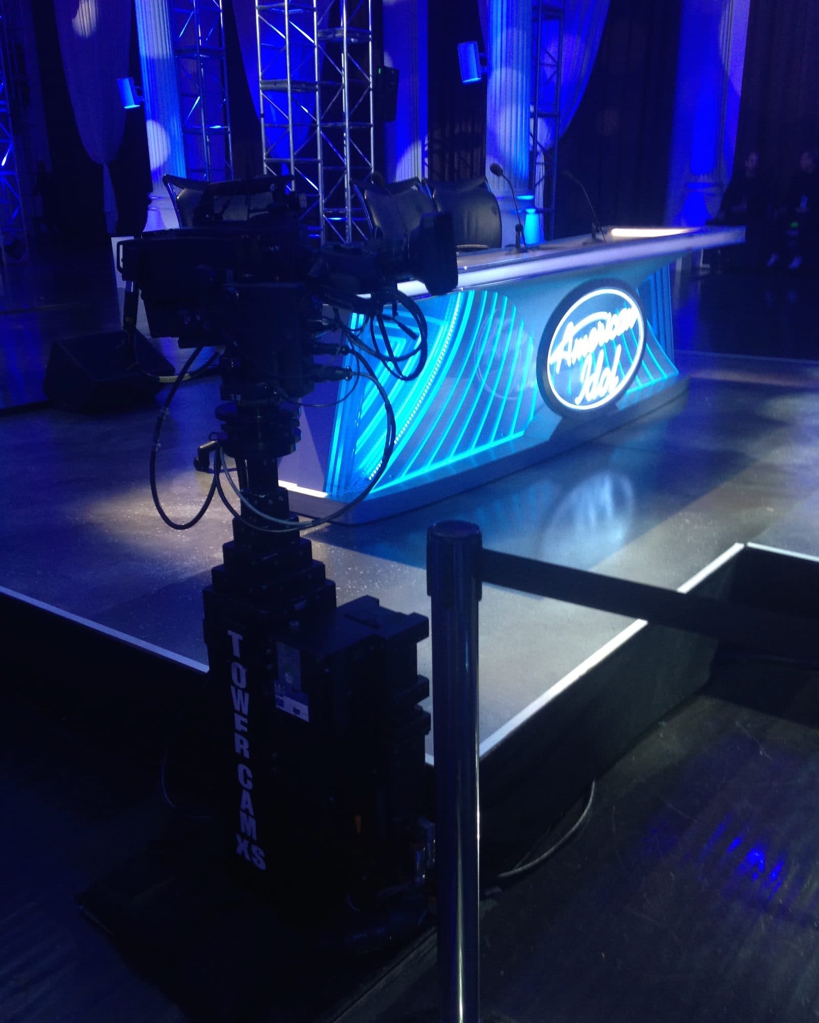 MAT Towercam XS+ column, marked Towercam, carrying a camera beside the blue-lit American Idol stage