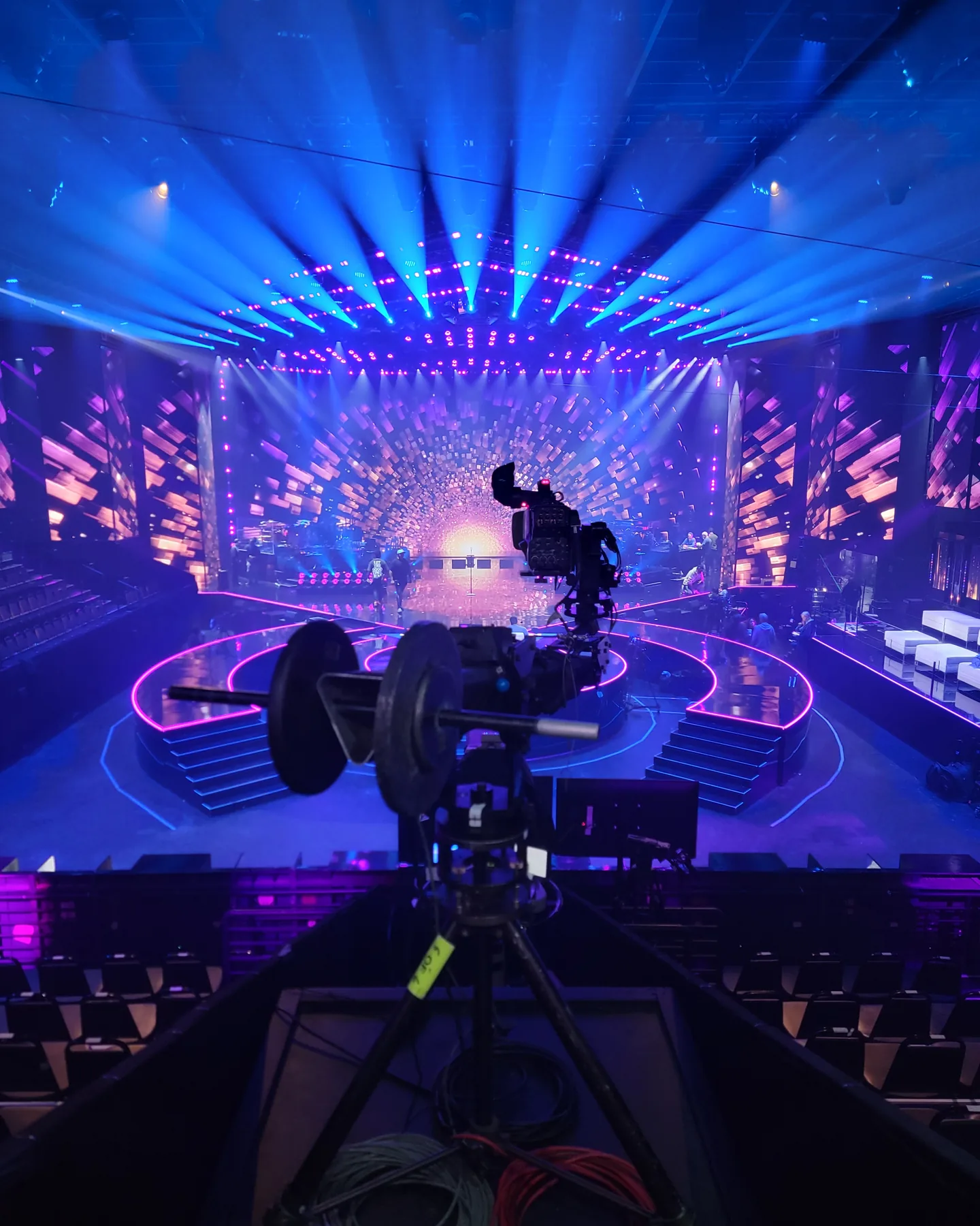 Jimmy Jib camera head and counterweights on a platform facing a blue-lit television stage
