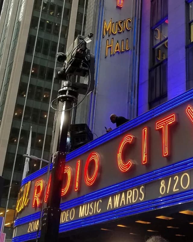 Standard Towercam carrying a camera outside Radio City Music Hall beneath the lit marquee